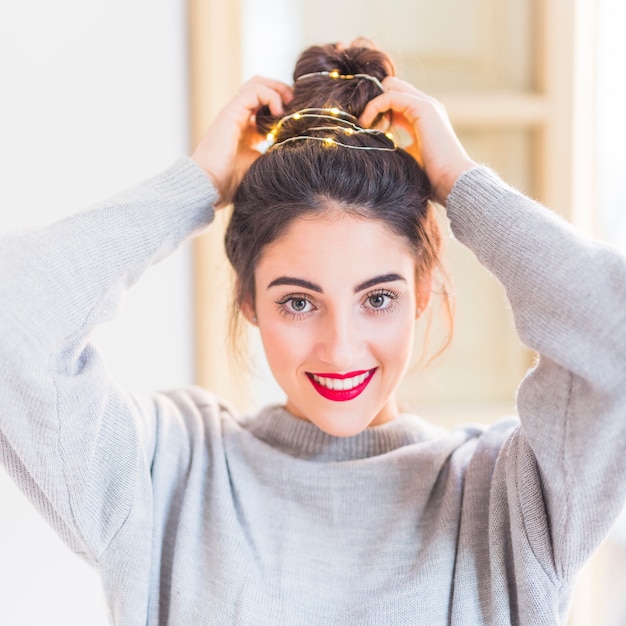 Mujer en gris con guirnalda de luces en pelo.