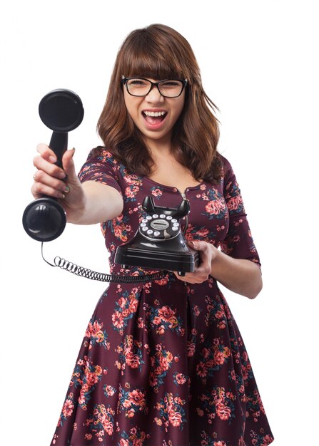 Mujer gritando con un teléfono antiguo en la mano