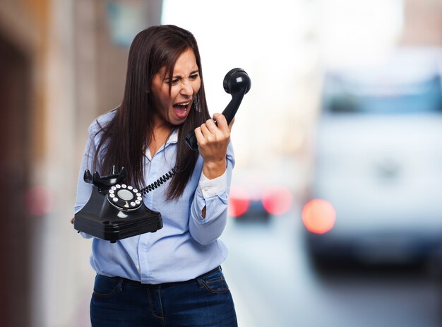 Mujer gritando a un teléfono antiguo