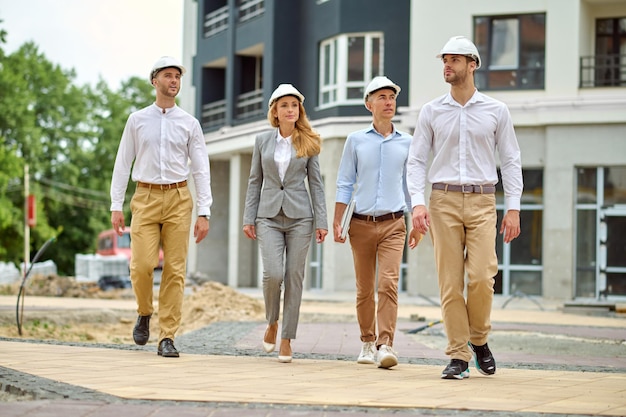 Mujer y grupo de hombres caminando en sitio en construcción