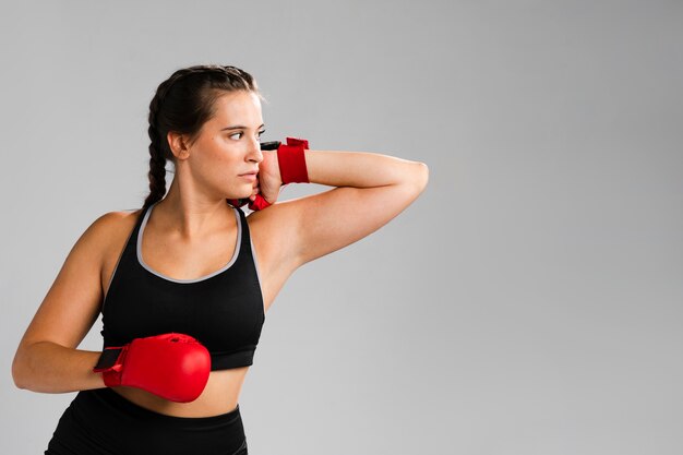 Mujer con guantes de box mirando a otro lado y copiar el fondo del espacio