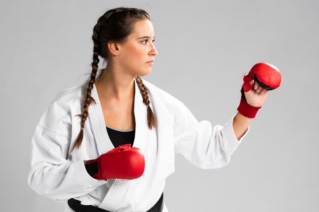 Mujer con guantes de box sobre fondo blanco.