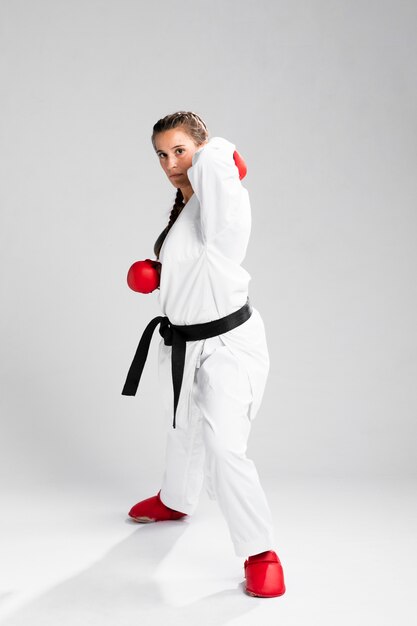 Mujer con guantes de box sobre fondo blanco.