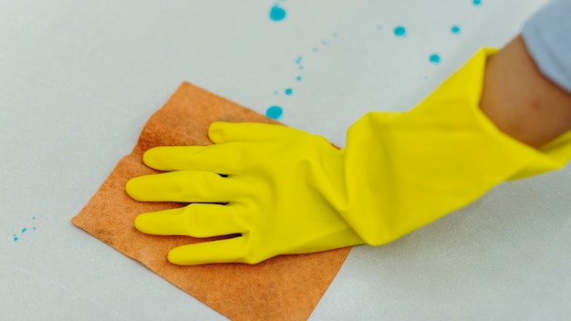 Mujer con guantes de goma amarillos y limpieza de la superficie