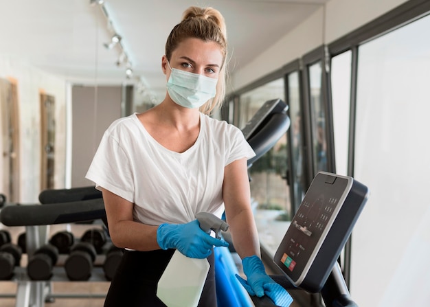 Mujer con guantes de limpieza de equipos de gimnasia durante la pandemia