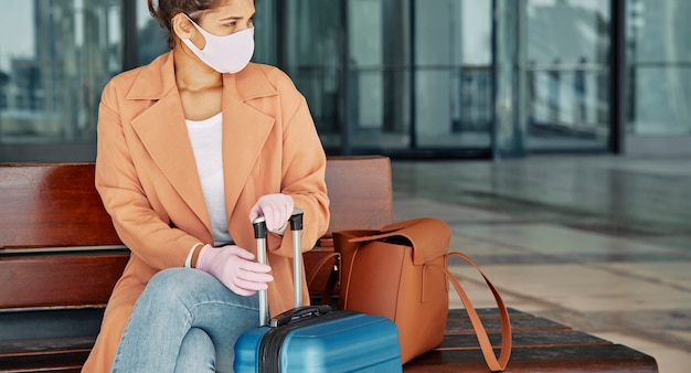 Mujer con guantes y mascarilla médica en el aeropuerto durante la pandemia