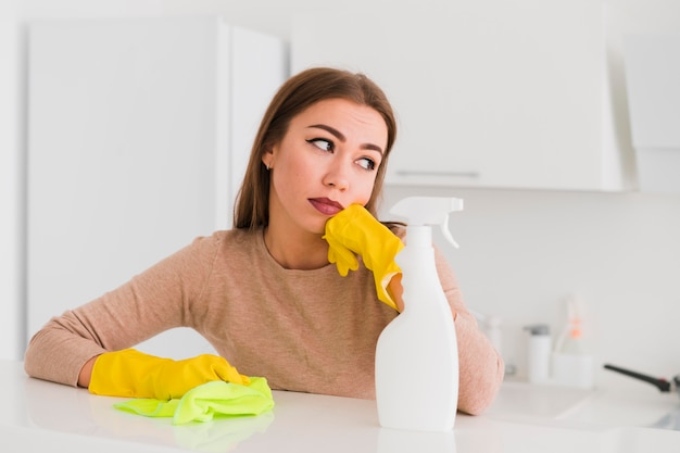 Mujer con guantes y productos de limpieza.