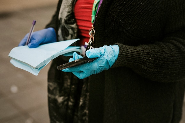 Mujer con guantes protectores de látex y sosteniendo un teléfono.