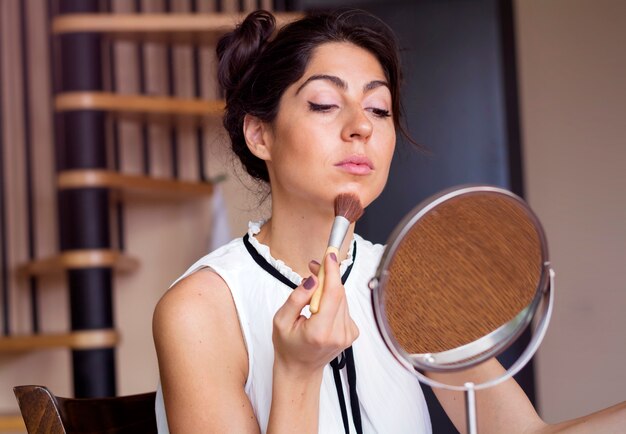 Mujer guapa aplicándose polvos en la cara