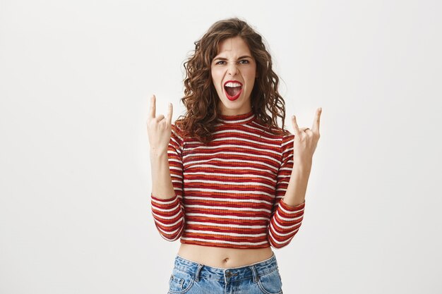 Mujer guapa descarada gritando y mostrando gesto de heavy metal