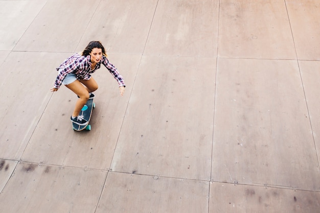 Mujer guapa patinando con la patineta