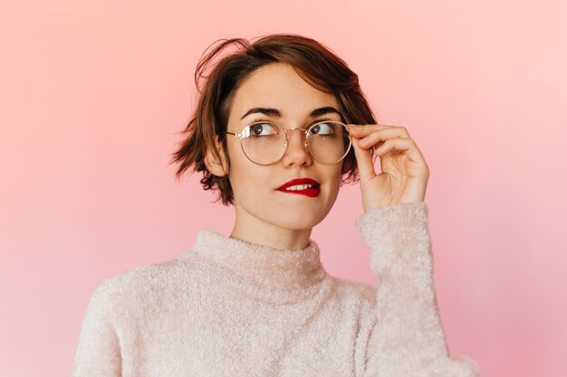 Mujer guapa pensativa tocando gafas