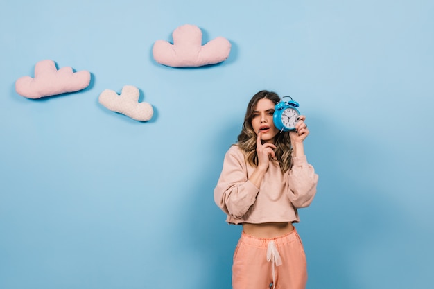 Mujer guapa posando en la pared azul con nubes