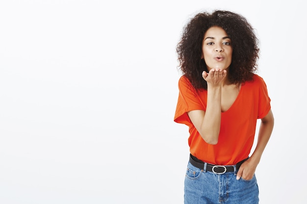 Mujer guapa saliente con peinado afro posando en el estudio