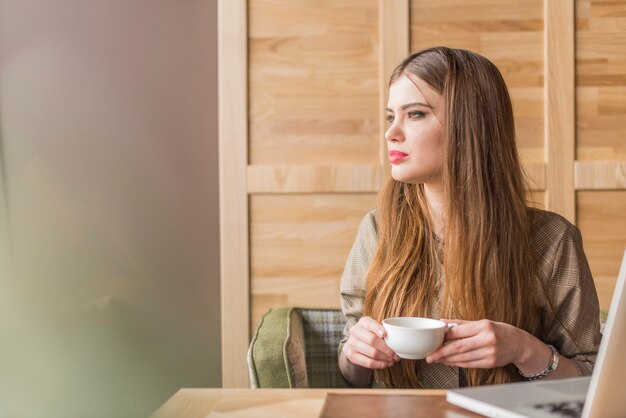 Mujer guapa con taza de té mirando hacia un lado