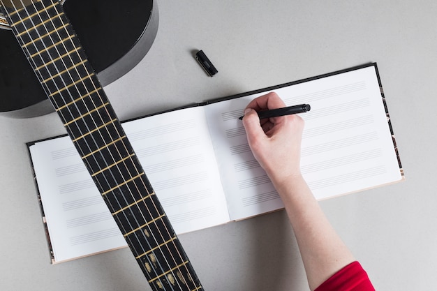 Mujer con guitara apuntando notas