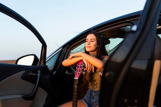 Mujer con guitarra en el asiento de su coche