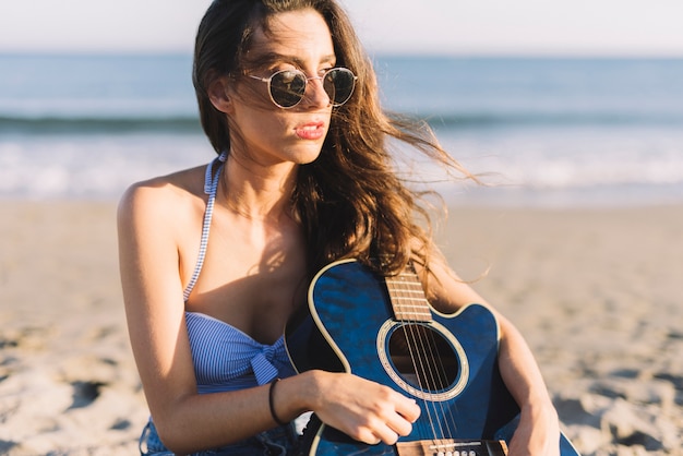 Mujer con guitarra azul en la playa