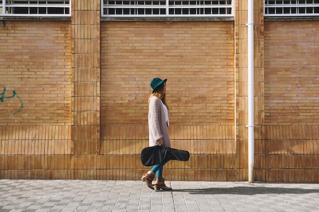 Mujer con guitarra caminando por la calle