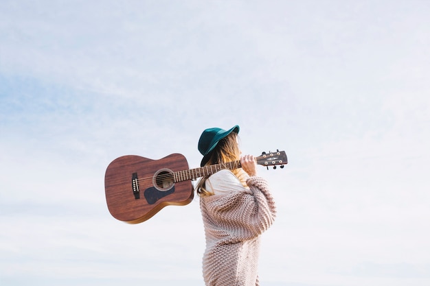 Mujer con guitarra caminando en la naturaleza