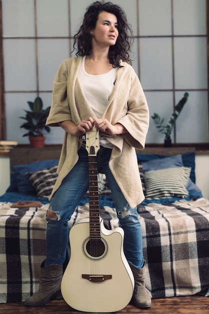 Mujer con guitarra en dormitorio