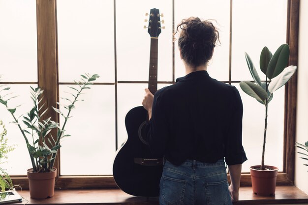Mujer con guitarra mirando por la ventana