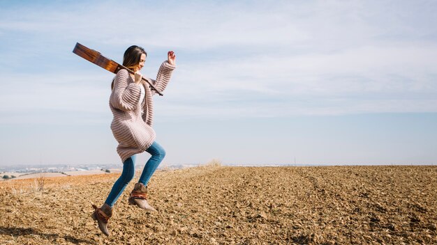 Mujer con guitarra saltando en el campo