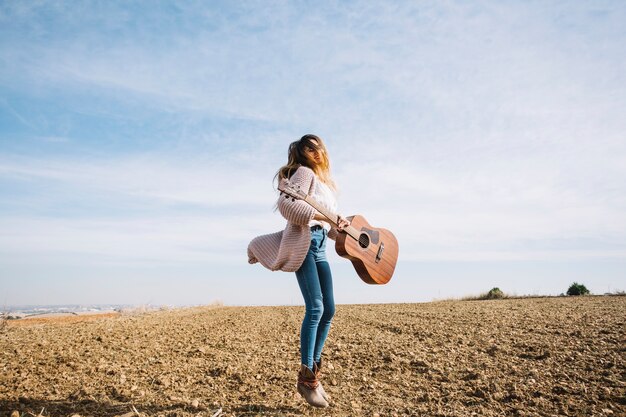 Mujer con guitarra saltando en el campo