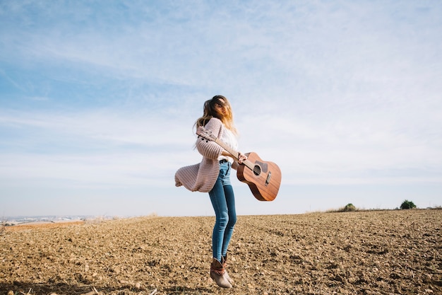 Mujer con guitarra saltando en el campo