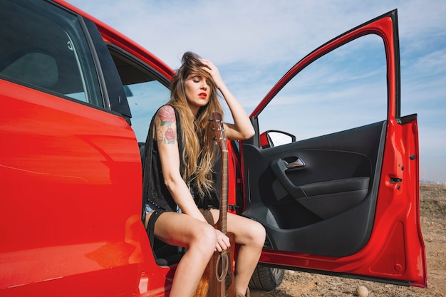 Mujer con guitarra sentado en el coche