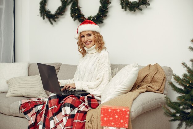 Mujer en una habitación. Rubia con un suéter blanco. Señora con portátil.