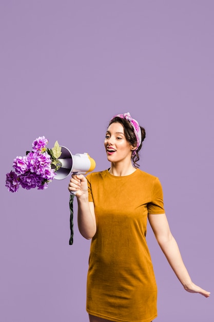 Mujer hablando por el megáfono bloqueado por flores
