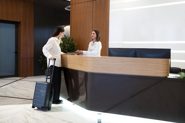 Mujer hablando con una recepcionista de hotel en el vestíbulo