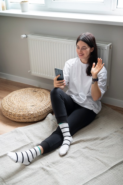 Mujer hablando por su teléfono inteligente en casa durante la cuarentena