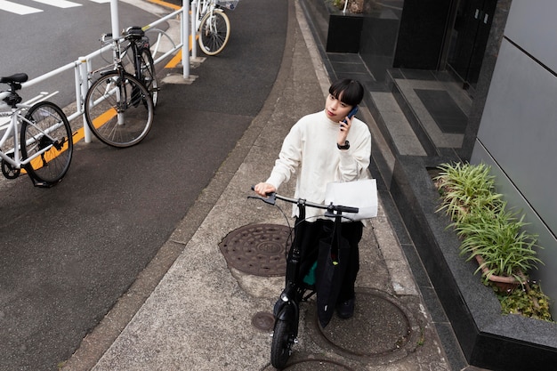 Foto gratuita mujer hablando por teléfono y con bicicleta eléctrica en la ciudad