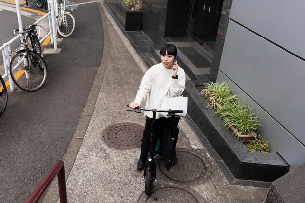 Mujer hablando por teléfono y con bicicleta eléctrica en la ciudad