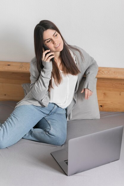 Mujer hablando por teléfono cerca de la computadora portátil