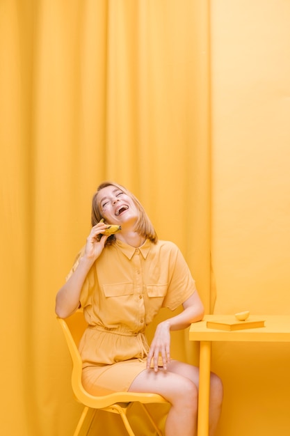 Mujer hablando por teléfono en escenario amarillo