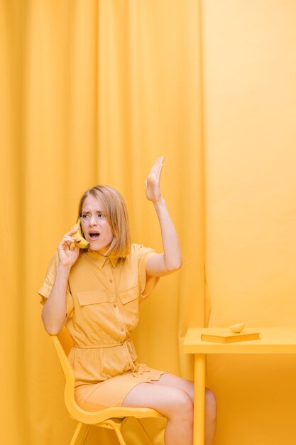 Mujer hablando por teléfono en escenario amarillo