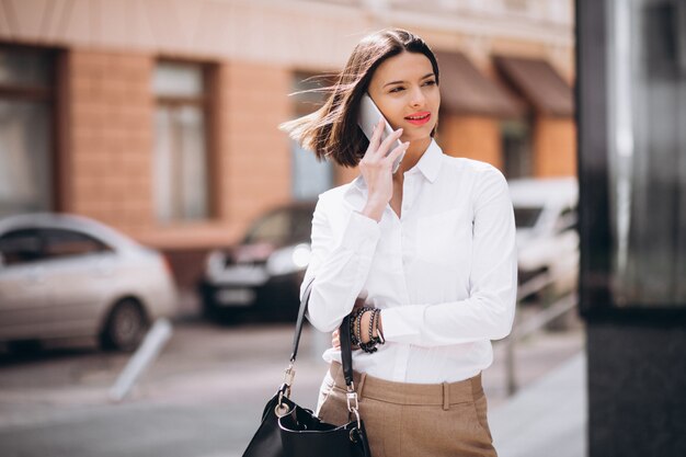 Mujer hablando por teléfono fuera de las calles de la ciudad