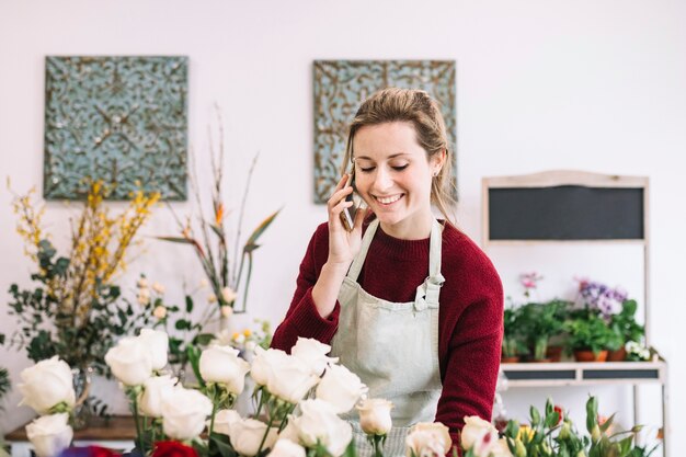 Mujer hablando en teléfono inteligente en tienda de flores