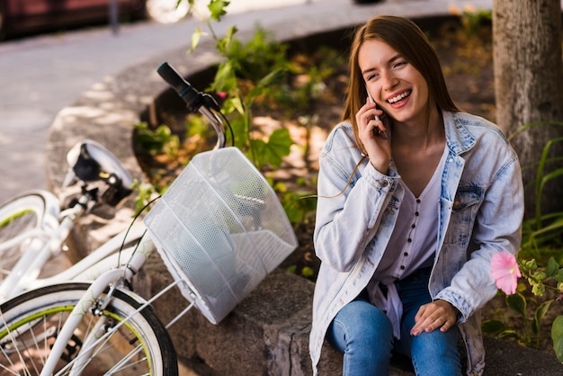 Foto gratuita mujer hablando por teléfono junto a la bicicleta