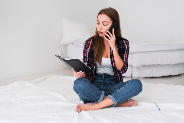 Mujer hablando por teléfono con un libro en la mano