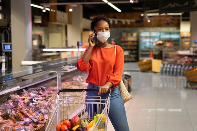 Mujer hablando por teléfono mientras compra en el supermercado