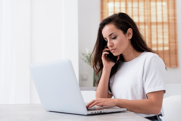 Foto gratuita mujer hablando por teléfono mientras trabajaba en una computadora portátil