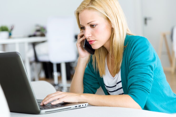 Foto gratuito mujer hablando por teléfono mirando portátil