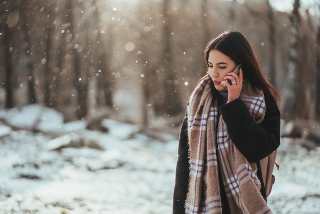 Mujer hablando por teléfono móvil. Mujer sonriente que habla en el teléfono móvil en día de invierno frío.