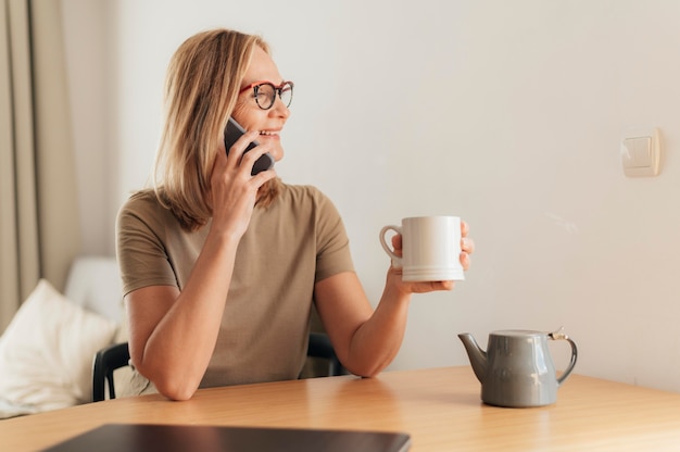 Mujer hablando por teléfono y tomando café durante la cuarentena