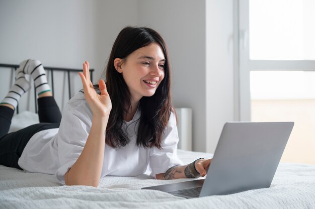 Mujer hablando y usando su laptop en casa durante la cuarentena