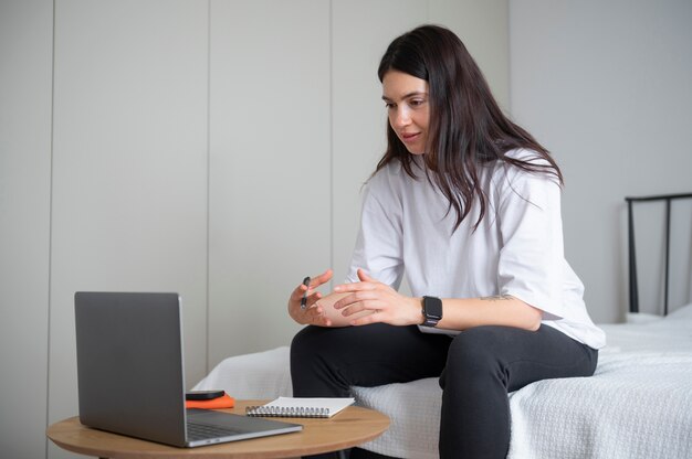 Mujer hablando y usando su laptop en casa durante la cuarentena